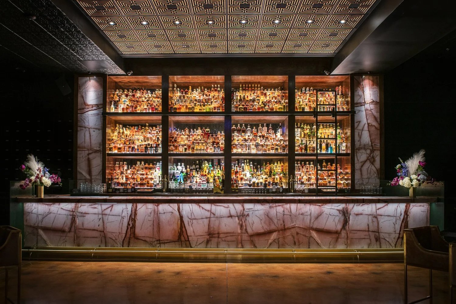 Backlit whiskey wall behind a marble bar